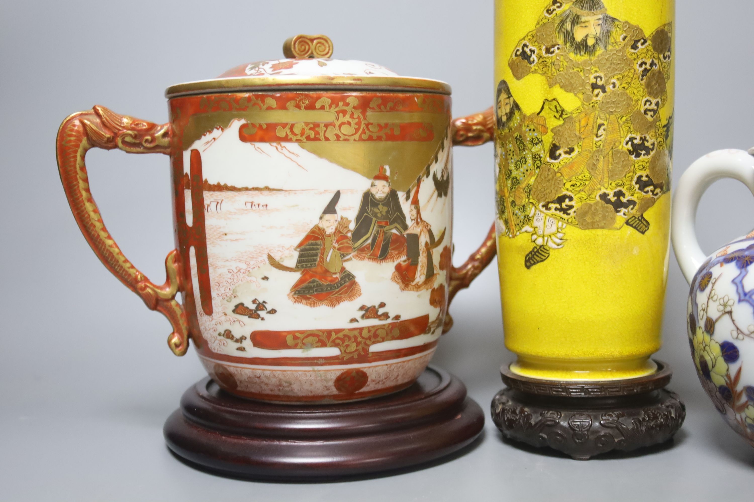 A Satsuma yellow ground vase, a Kutani twin handled cup and cover, a Fukugawa Imari jug and an Imari koro and cover 27cm, three wood stands
